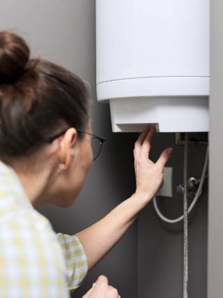 femme régule la température sur un chauffe eau électrique