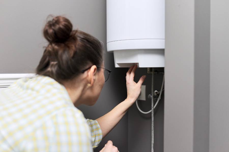 femme régule la température sur un chauffe eau électrique